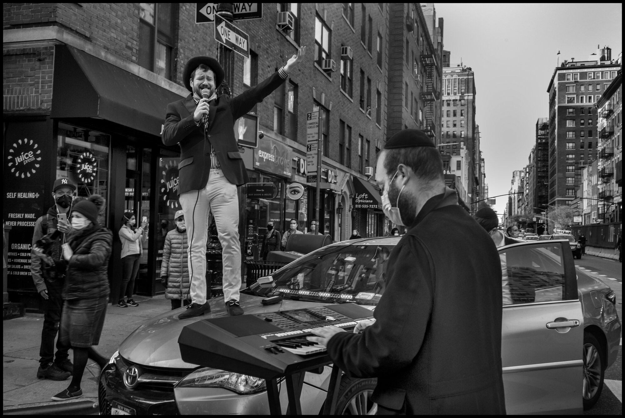  Young man sings from atop a car, “America the Beautiful”, at 7pm on Mother’s Day.  May 10, 2020. © Peter Turnley.   ID# 42-002 