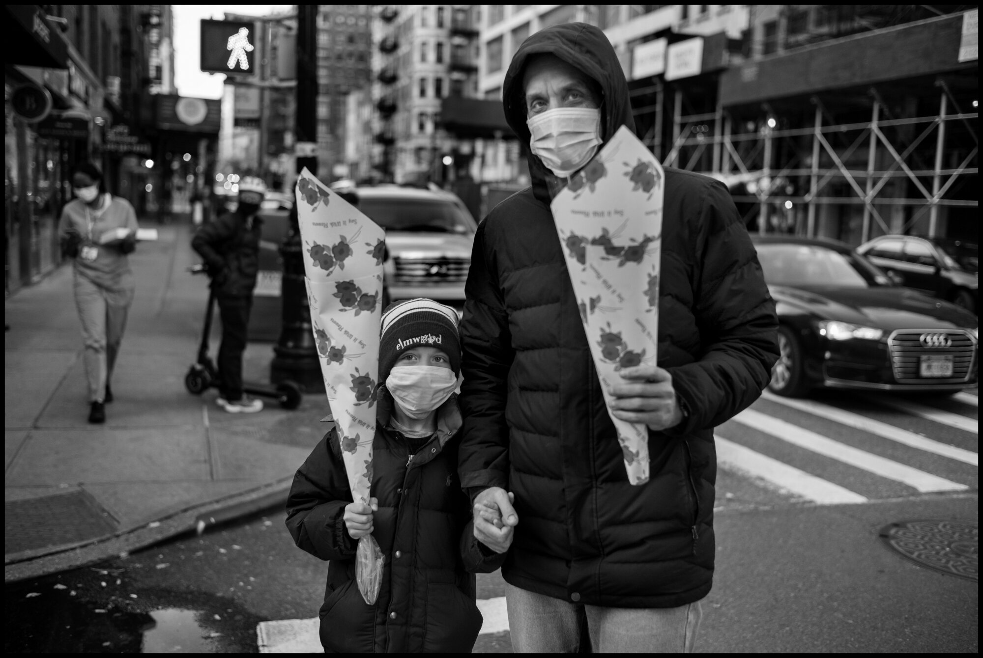  The night before Mother’s Day, a father, Mike, and his son, Alexander, pass by the corner of 77th and Lexington with flowers in their hand for Alexander’s mother, Anastasia.   May 9, 2020. © Peter Turnley.   ID# 42-004 