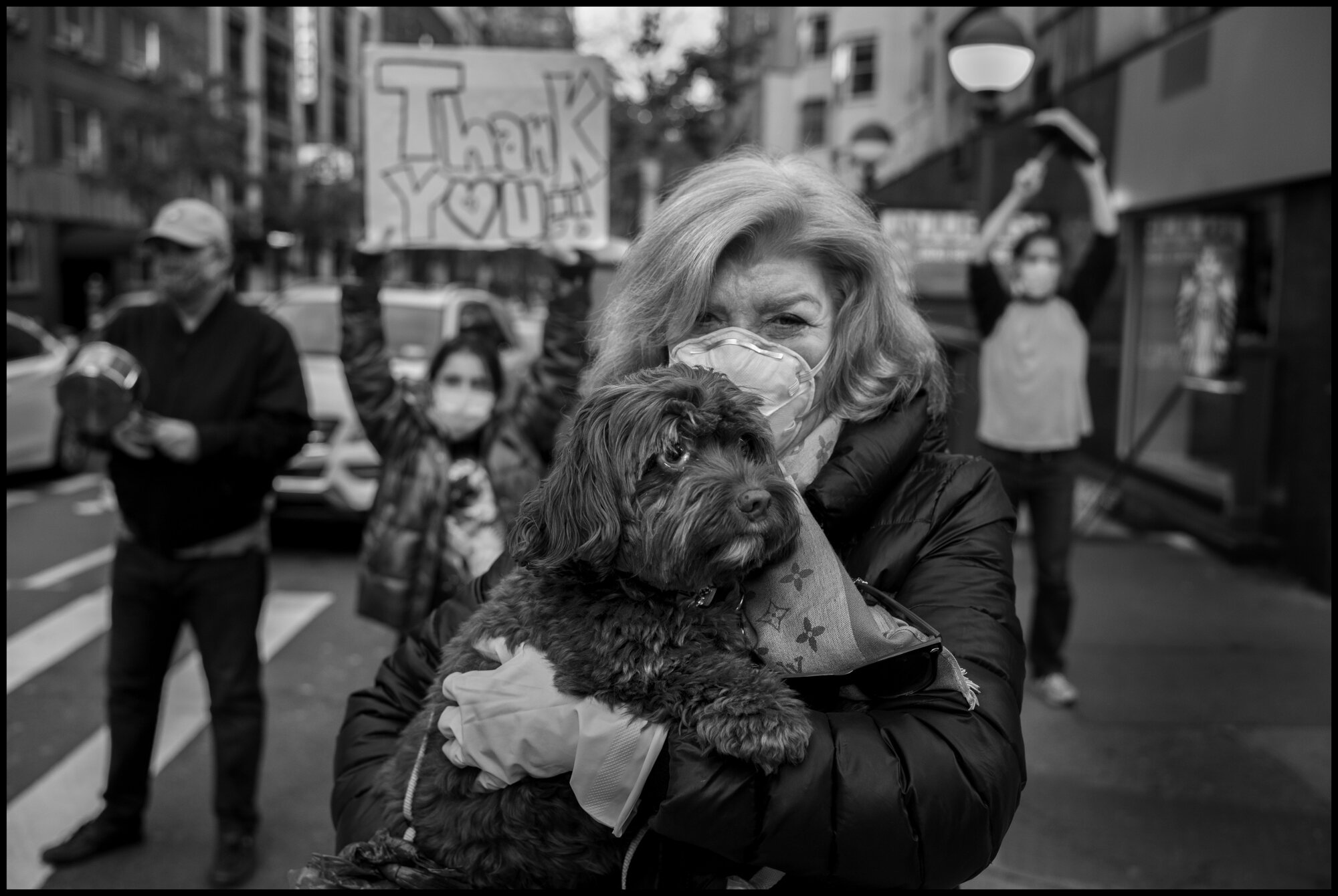  A resident of the Upper Eastside in New York City cheers on the healthcare and essential workers, in front of Lenox Hill Hospital.  May 9, 2020. © Peter Turnley.   ID# 42-008 