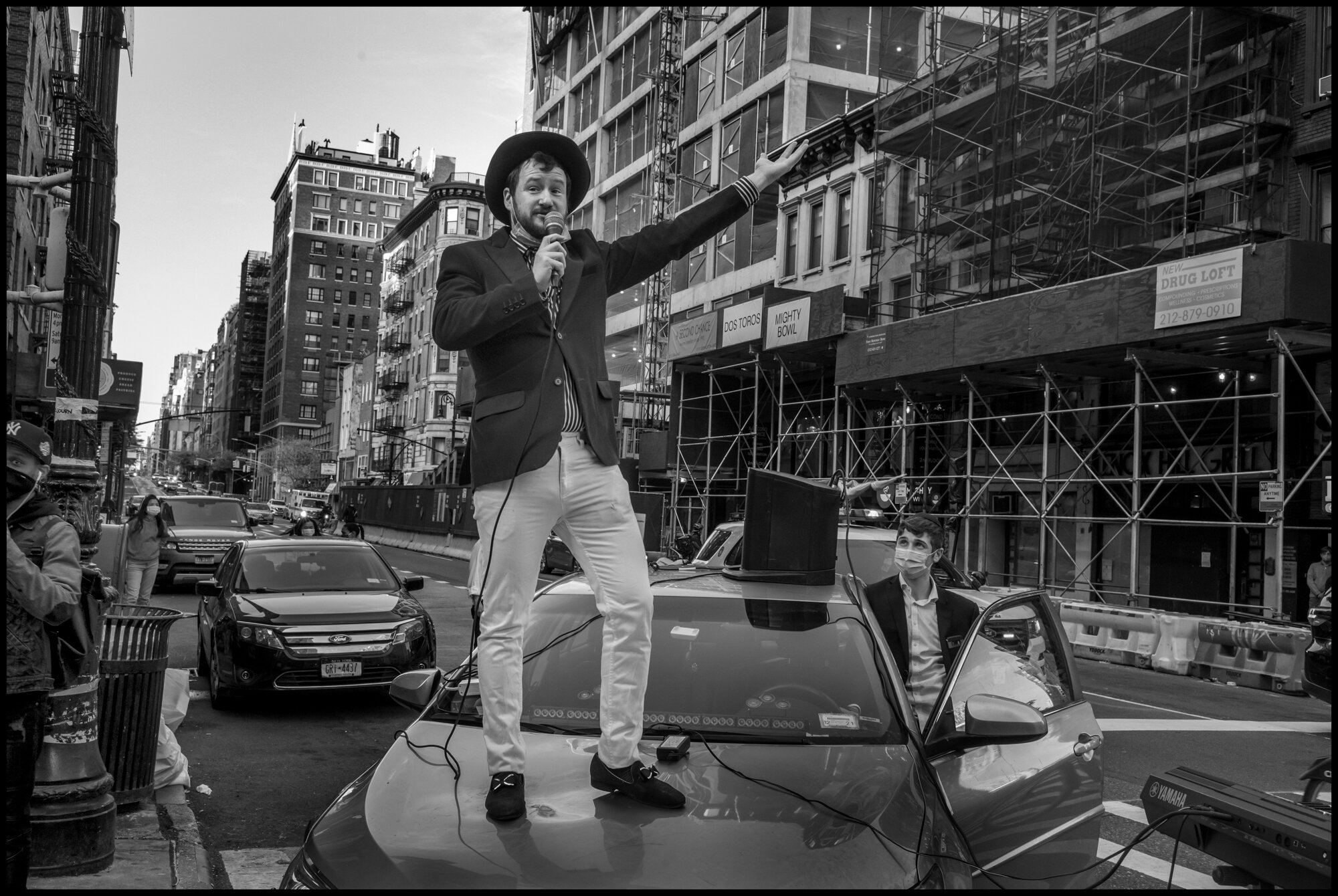  Young man sings from atop a car, “America the Beautiful”, at 7pm on Mother’s Day.  May 10, 2020. © Peter Turnley.   ID# 42-012 