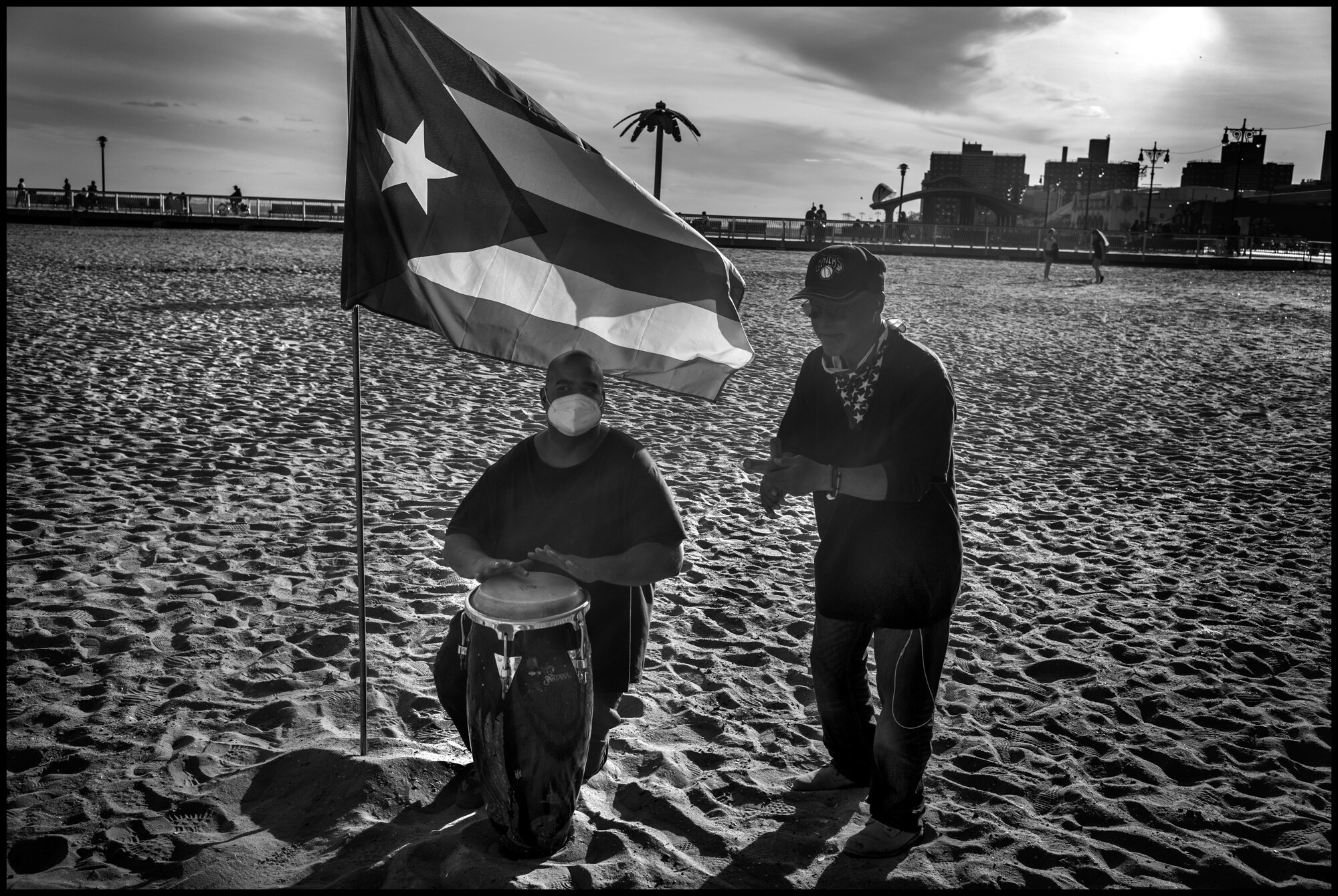  “Bear”, wearing a mask, plays music with a friend, on a gorgeous spring day at Coney Island.   May 16, 2020. © Peter Turnley.   ID# 49-003 