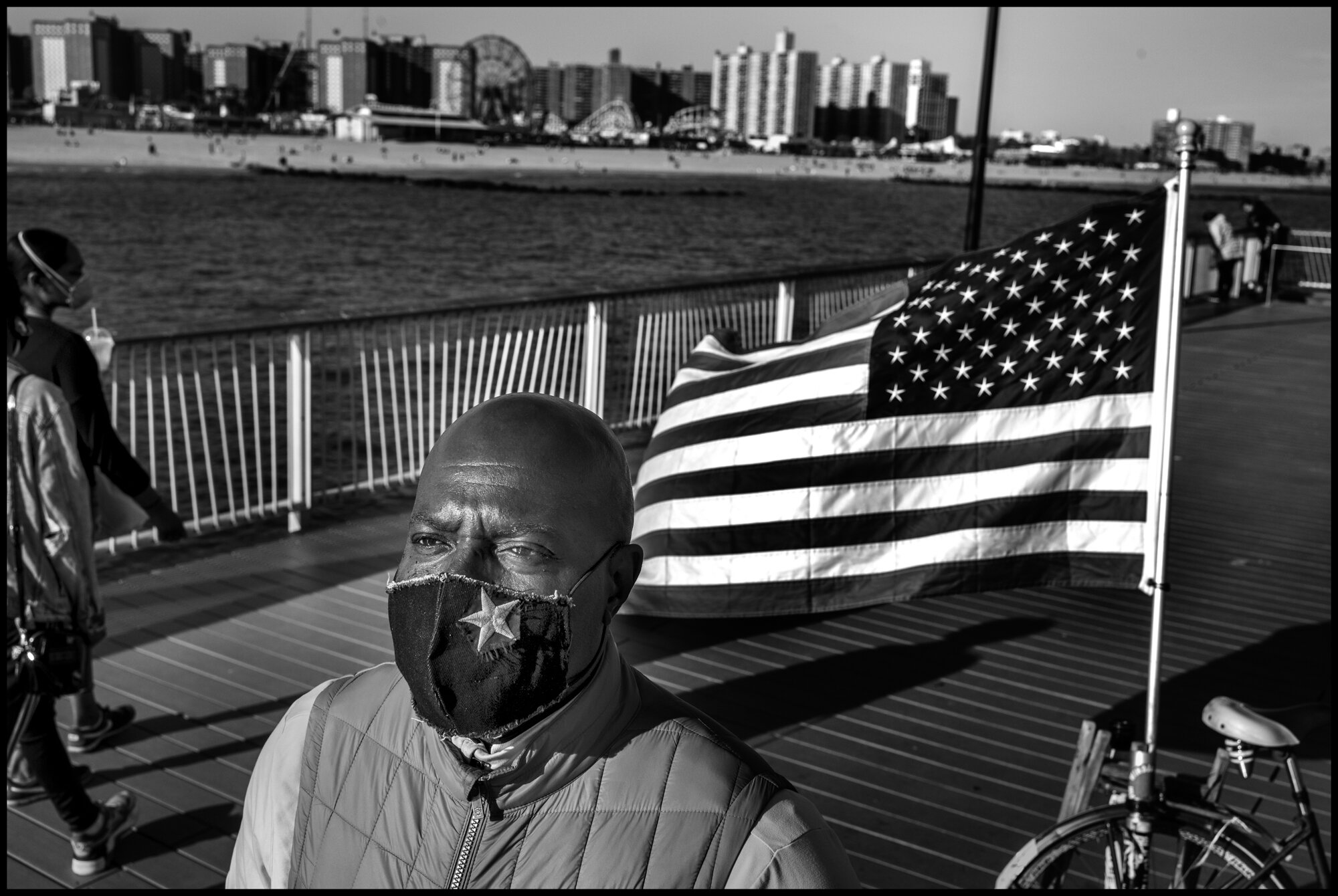  Johnathan, from Brooklyn, is a veteran who comes every day with a US flag to the pier. Coney Island, New York.  May 16, 2020. © Peter Turnley.  ID# 49-013 