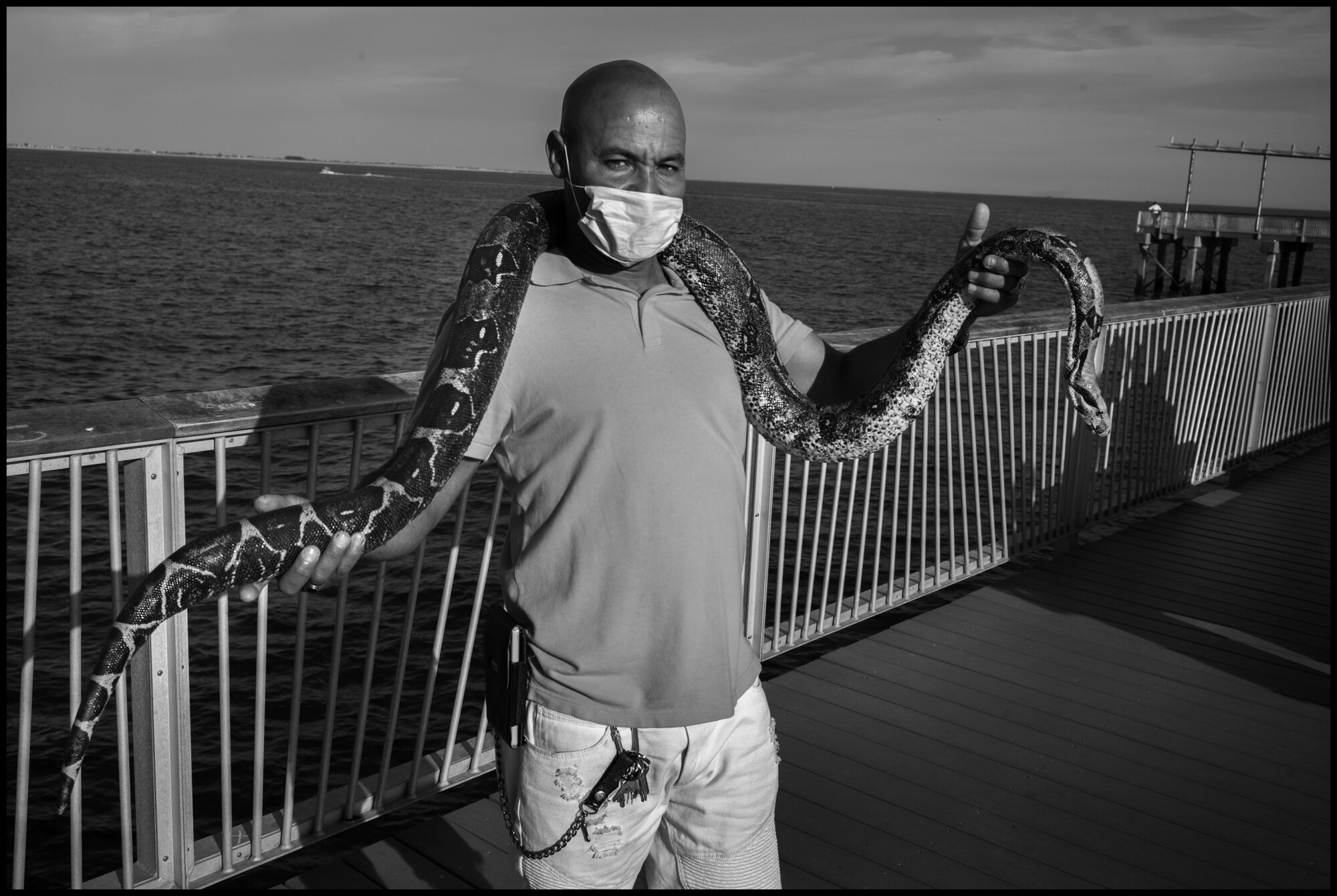  Alberto wearing a mask is now back at Coney Island with his python. Coney Island, New York.  May 16, 2020. © Peter Turnley.  ID# 49-014 