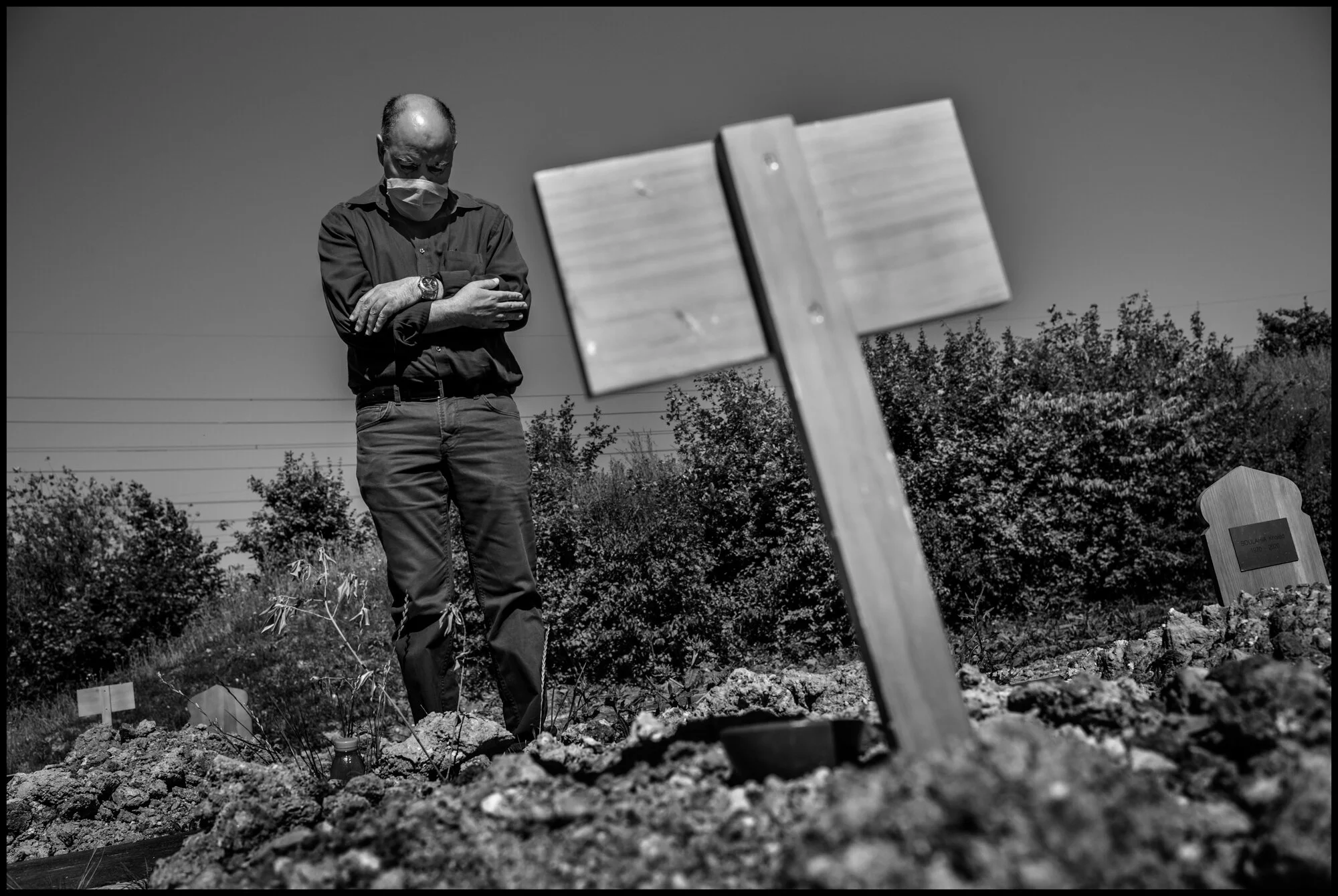  Abdelaziz, 64, praying in front of the grave of his mother, Rechid Embarka. St. Denis, France.   May 29, 2020. © Peter Turnley.  ID# P08-005 