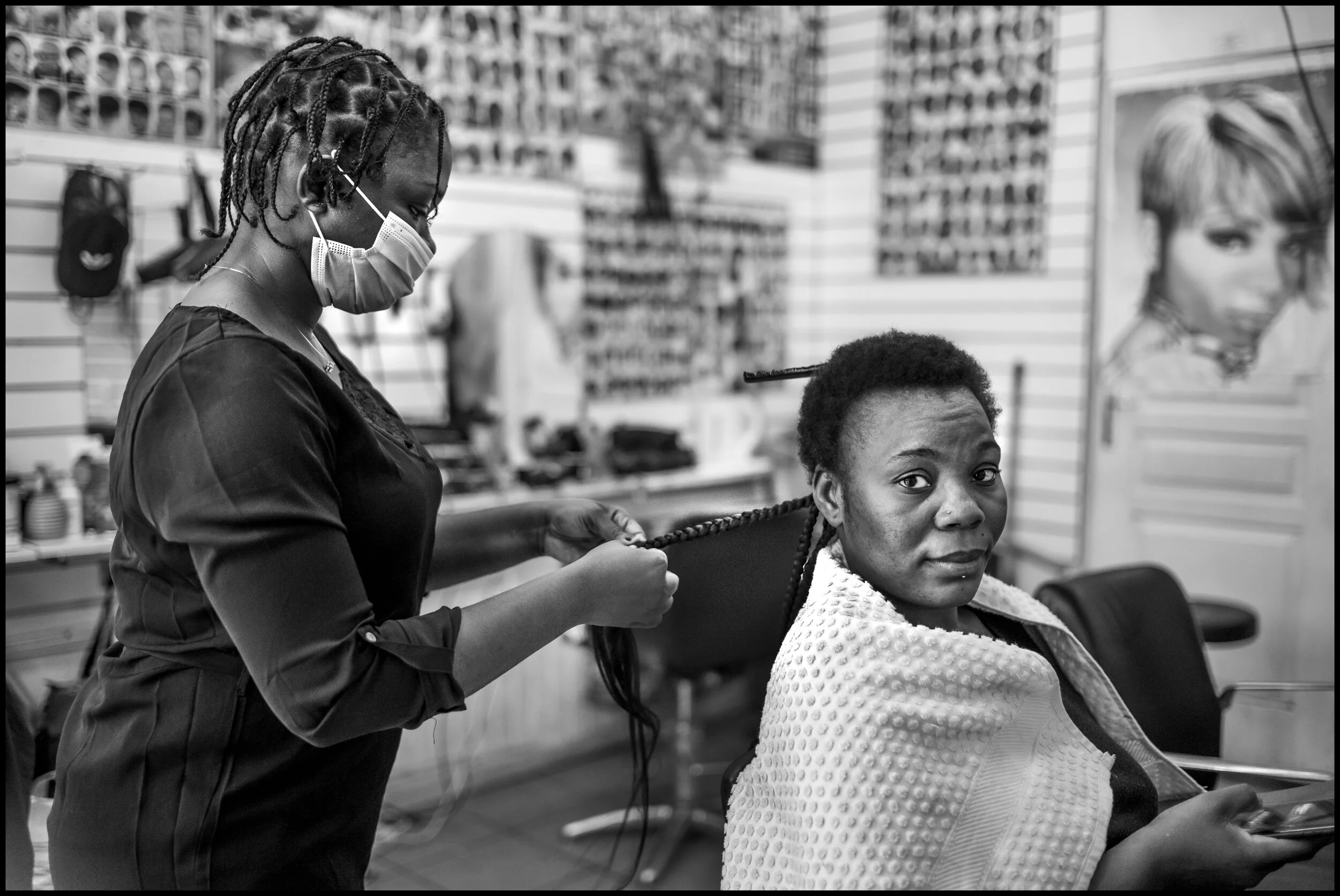  Josephine having her hair braided by Ange at a salon on rue Poulet near the Chateau Rouge Métro, Paris.  June 29, 2020. © Peter Turnley.   ID# P47-001 