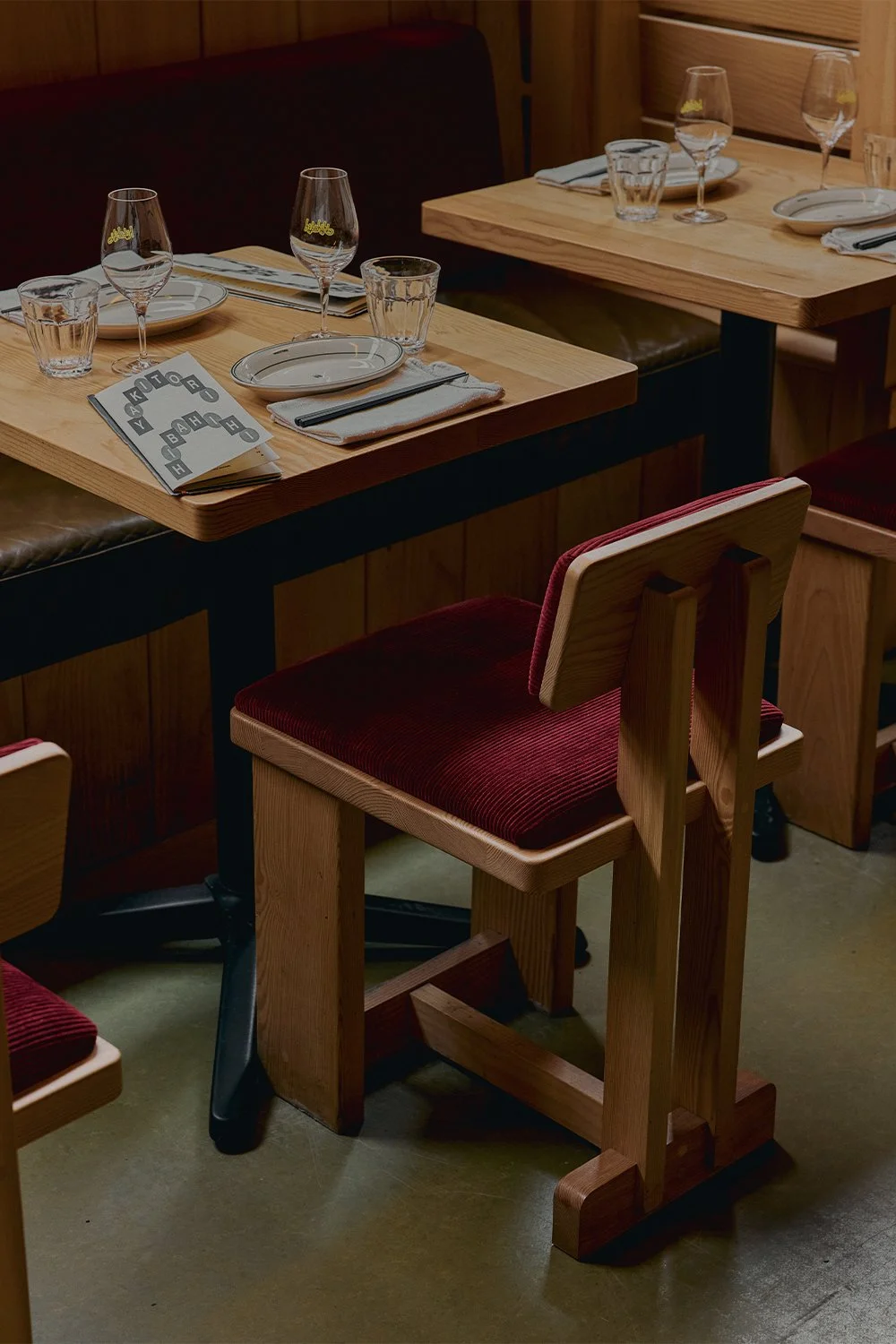 Custom-designed and built wood dining chairs and tables by Finkel with red upholstered seats at Hibahihi.