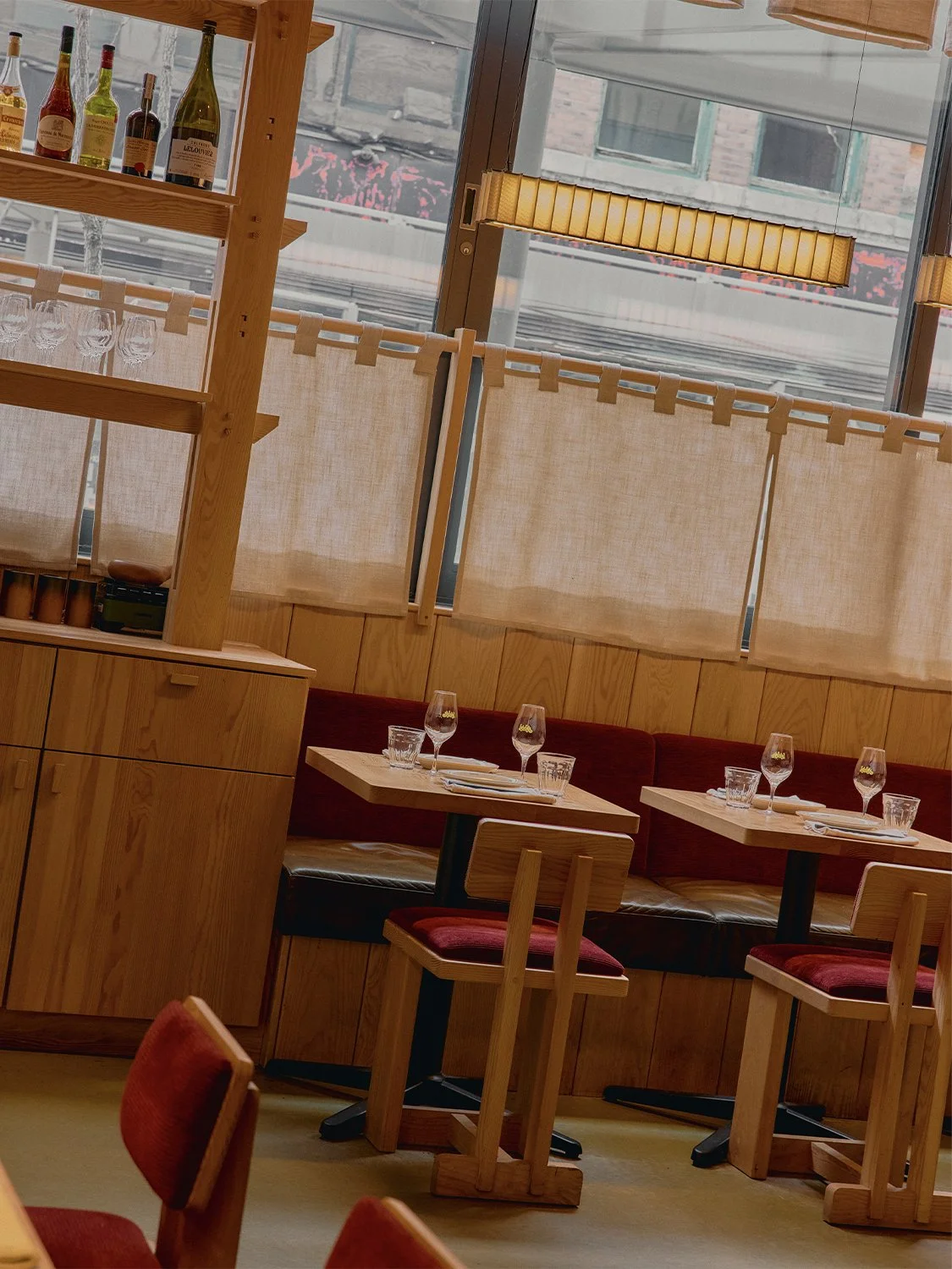 Dining area at Hibahihi with custom-designed and built wood seating by Finkel, linen window screens, and warm ambient lighting.