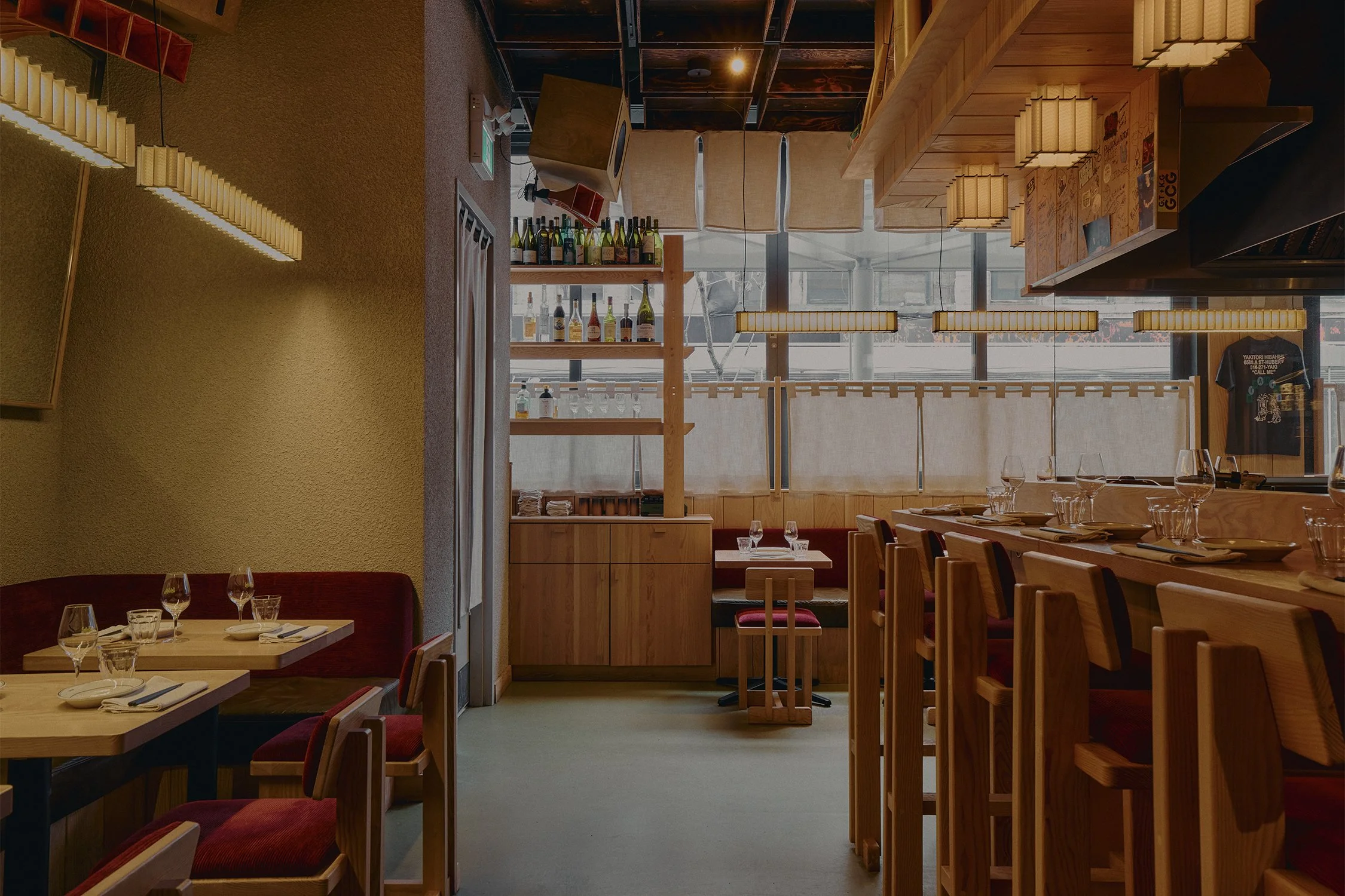 Dining area at Hibahihi with custom wood seating, open layout, and paper lantern lighting overlooking the street.