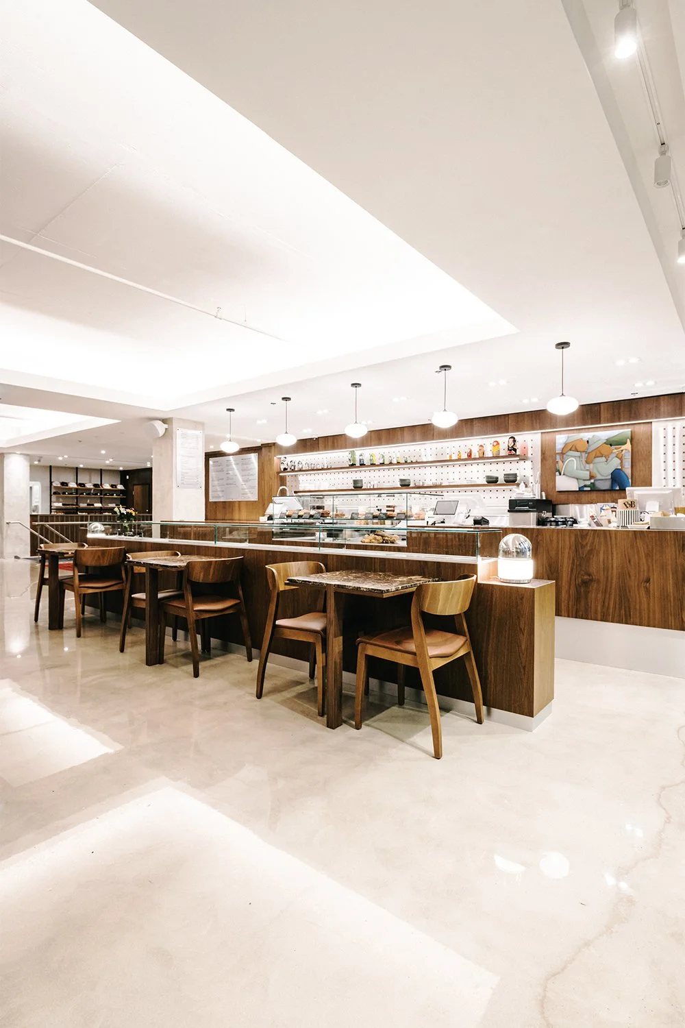 Empire café interior designed by Finkel', showcasing custom wood counters, aligned seating, and a refined contemporary hospitality design