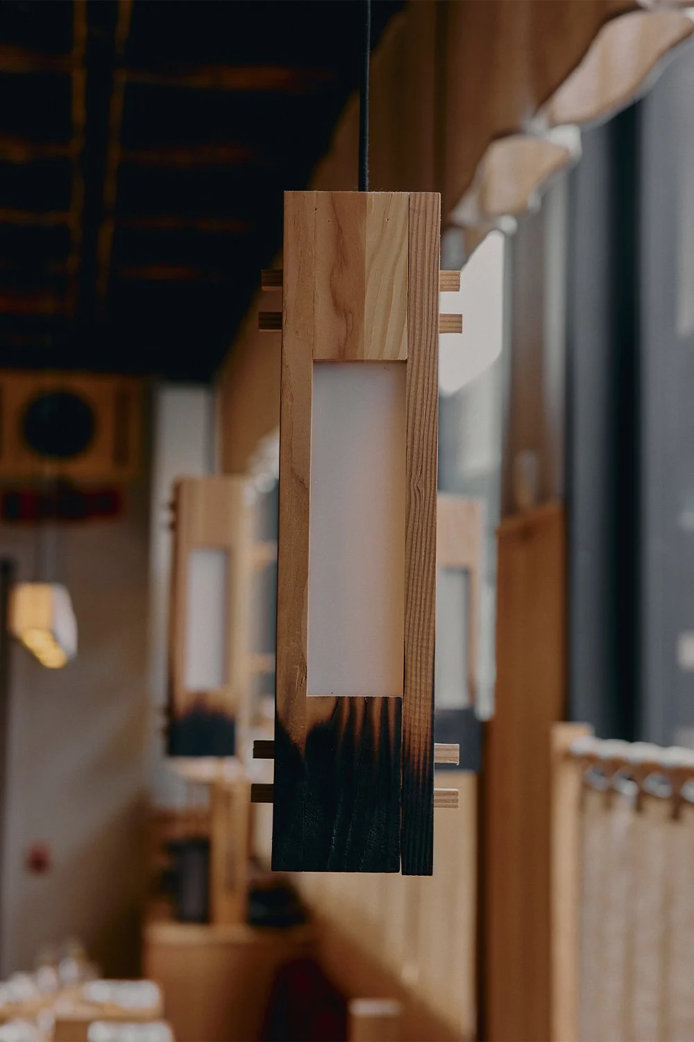 Custom wood pendant light designed and built by Finkel, featuring charred detailing and soft diffused glow.