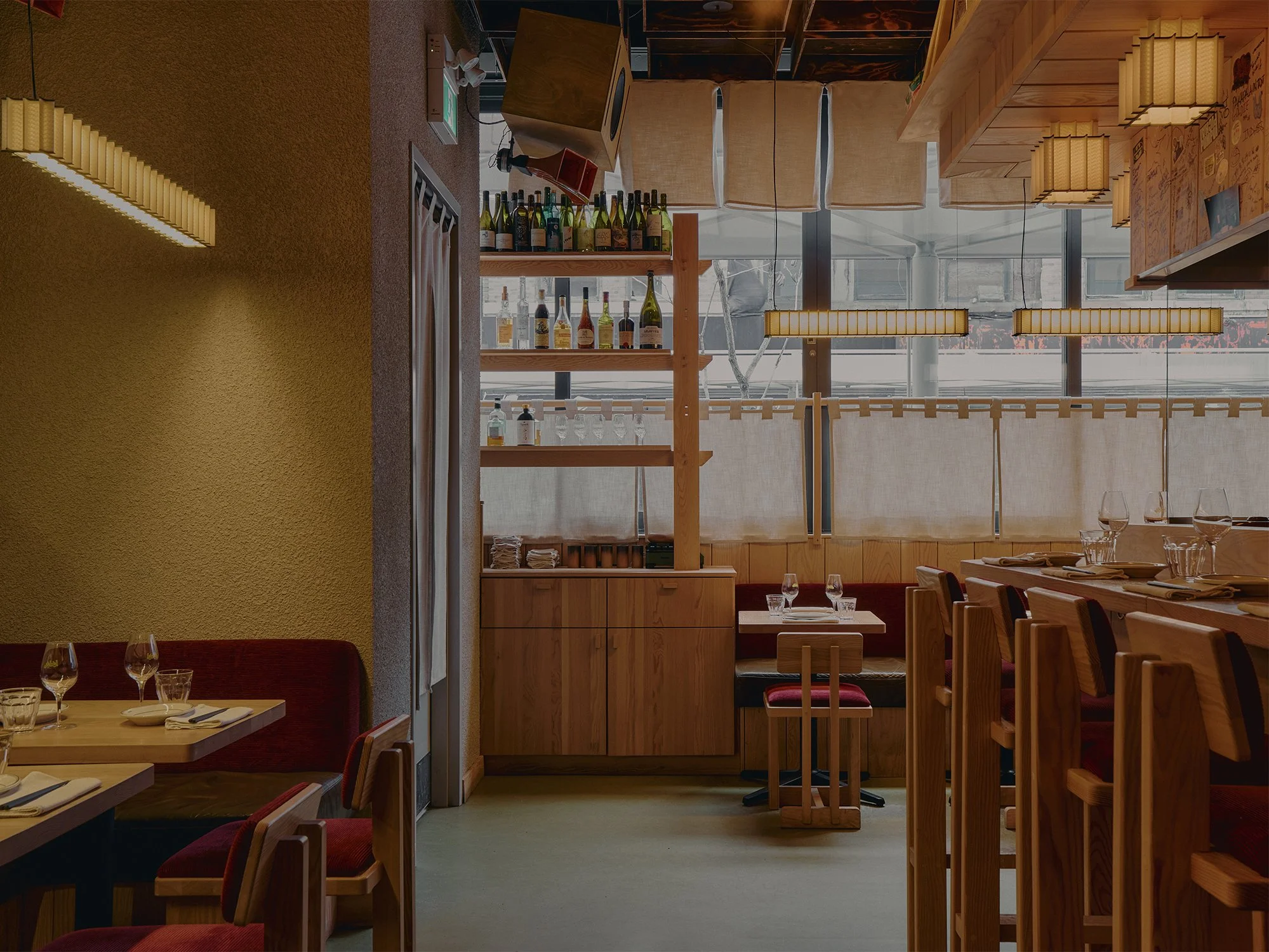 Dining area at Hibahihi with custom wood furniture designed and built by Finkel, linen window screens, and suspended lighting.