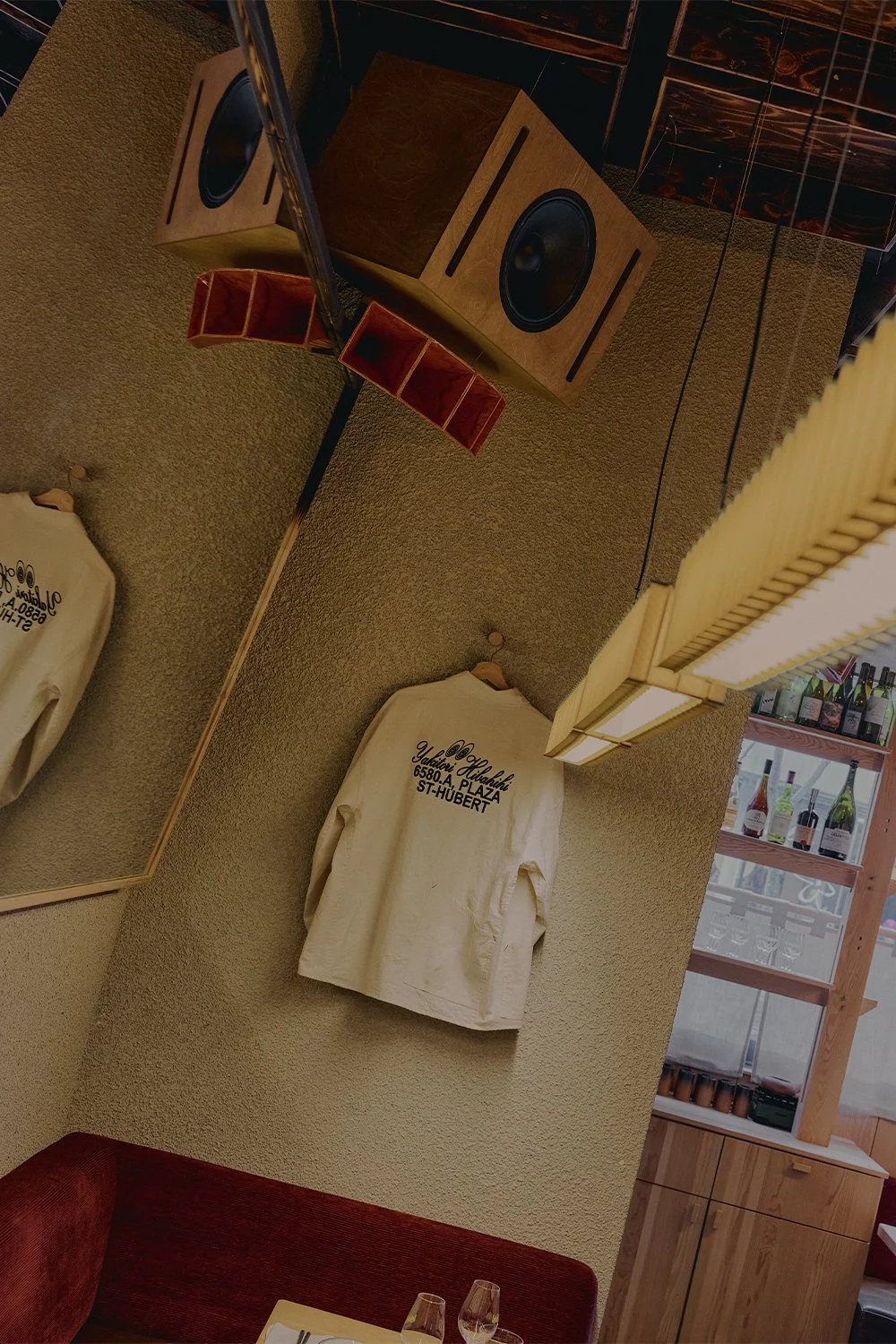 Interior detail at Hibahihi with custom wood elements by Finkel, a branded T-shirt display, and Mycoaudio sound system featured overhead.