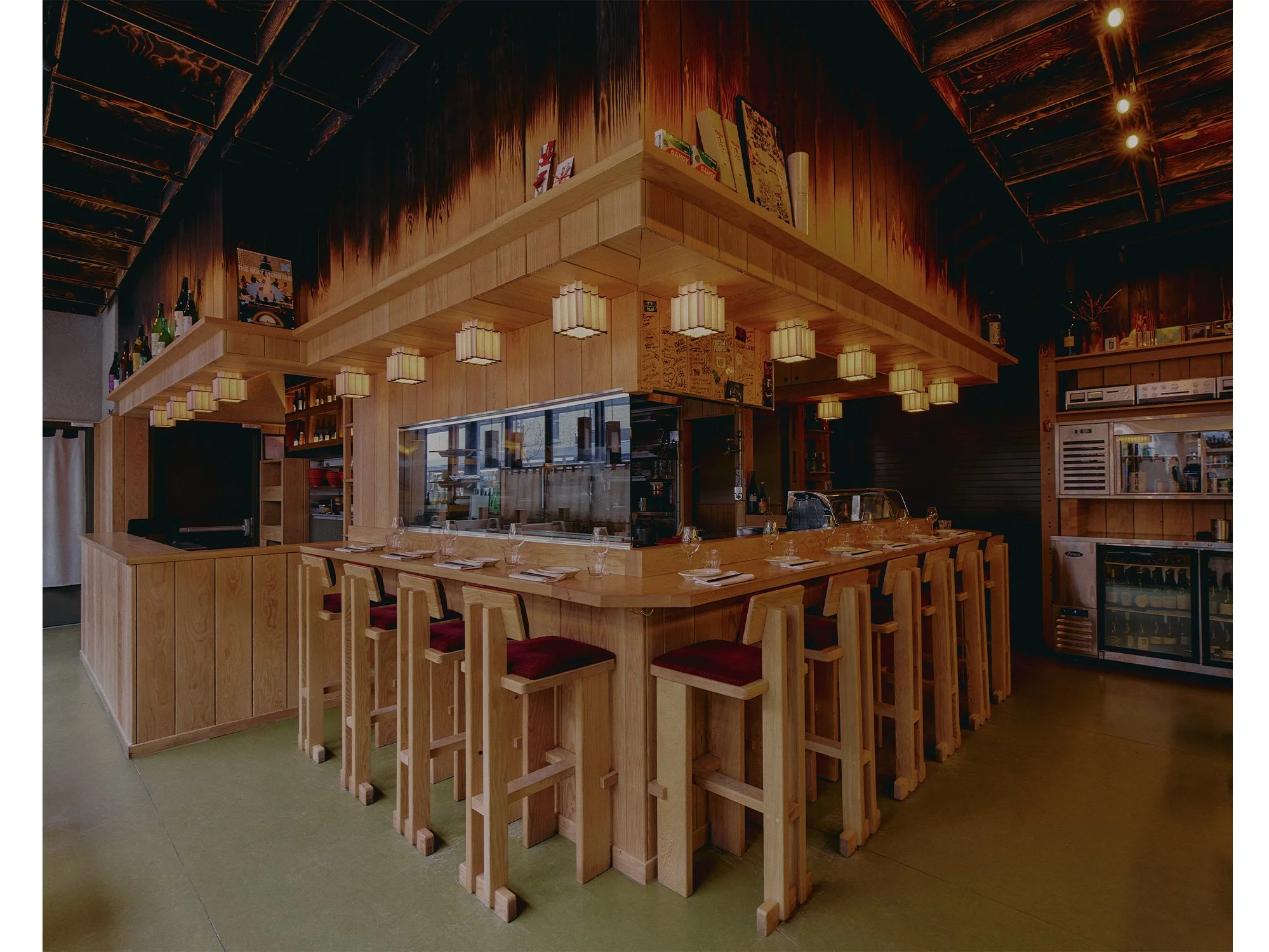 Open kitchen and bar at Hibahihi featuring custom-designed and built wood counter and seating by Finkel.