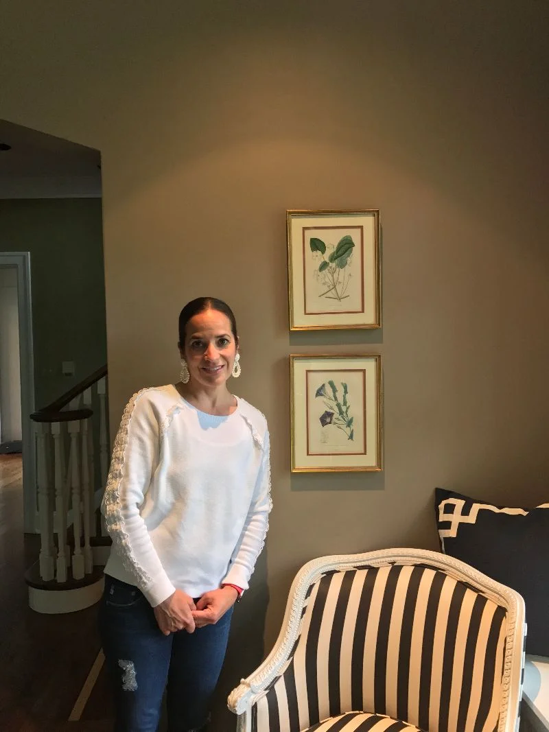  Christina Cripe is standing next to a pair of beautiful botanical prints. Her husband purchased them for her from the Antiques Show, before the separate Antiques and Modernism shows merged, likely about 2007. Christina says “He bought them for me af
