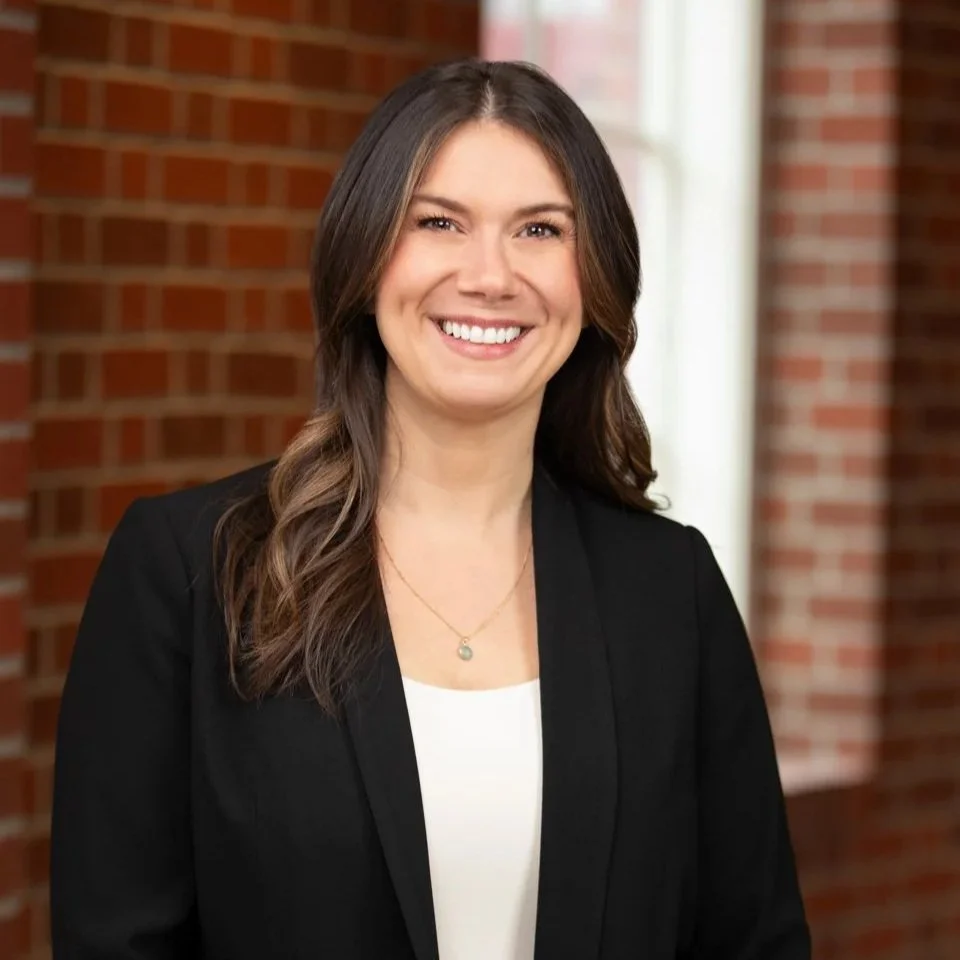 Professional woman in black blazer, location headshot with brick wall background, Portland OR