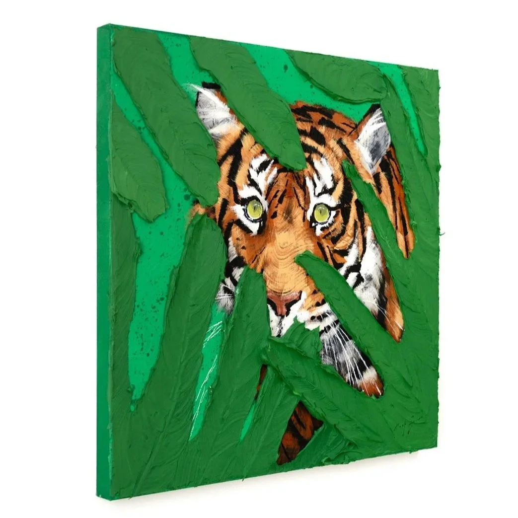 An angled view of an acrylic painting of a tiger’s green eyes emerging through thick painted leaves in a bold contemporary wildlife painting by Josh Brown.
