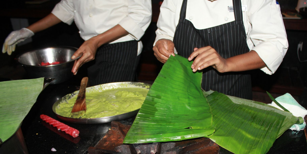 Warming banana leaves to make them flame retardant; making marinaded fish parcels in our cooking class, Marikulam