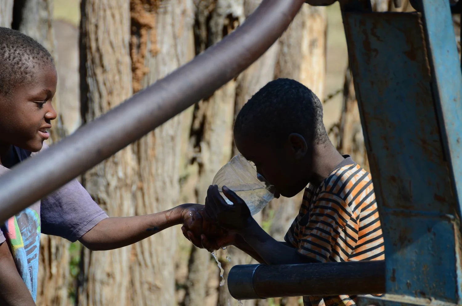   On a hot day, young brothers stop by for a cool drink before watering the livestock that they attend to for their community. &nbsp;These wells are a water source for both the community and animals.  