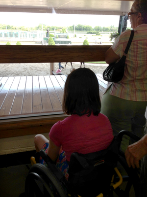 The jockey looked at the girl sitting on the rail and waved again as the entire family waved back and wished her luck.