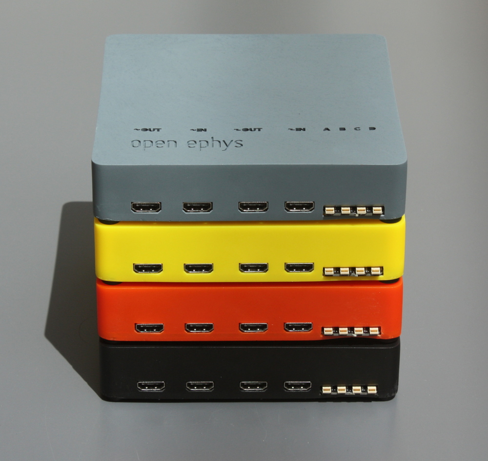 A stack of Open Ephys acquisition boards in cast-urethane cases. The next round of boards we make will have blue cases with translucent acrylic tops.