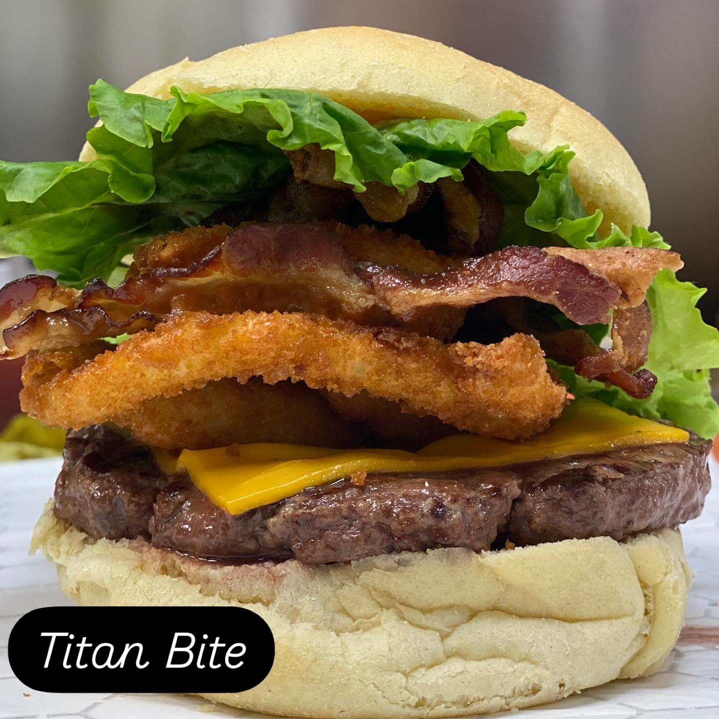 Fries? Cute.
But have you ever conquered the Titan Bite?
Stacked with crispy gourmet onion rings, melty cheddar, delicious bacon, lettuce, and our secret sauce&mdash;this 6oz beast isn&rsquo;t just a burger, it&rsquo;s a flex.

#TitanBite #BurgerBite