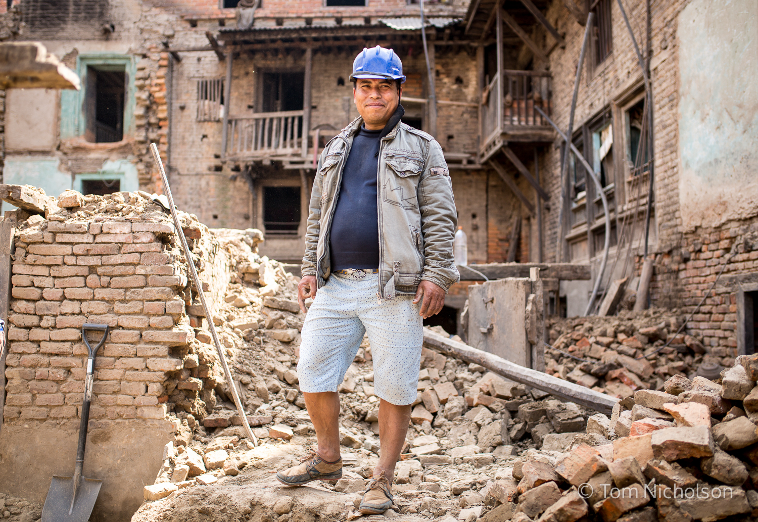 A man pauses whilst rebuilding his sister's house, which was destroyed by the April 2015 Earthquake.