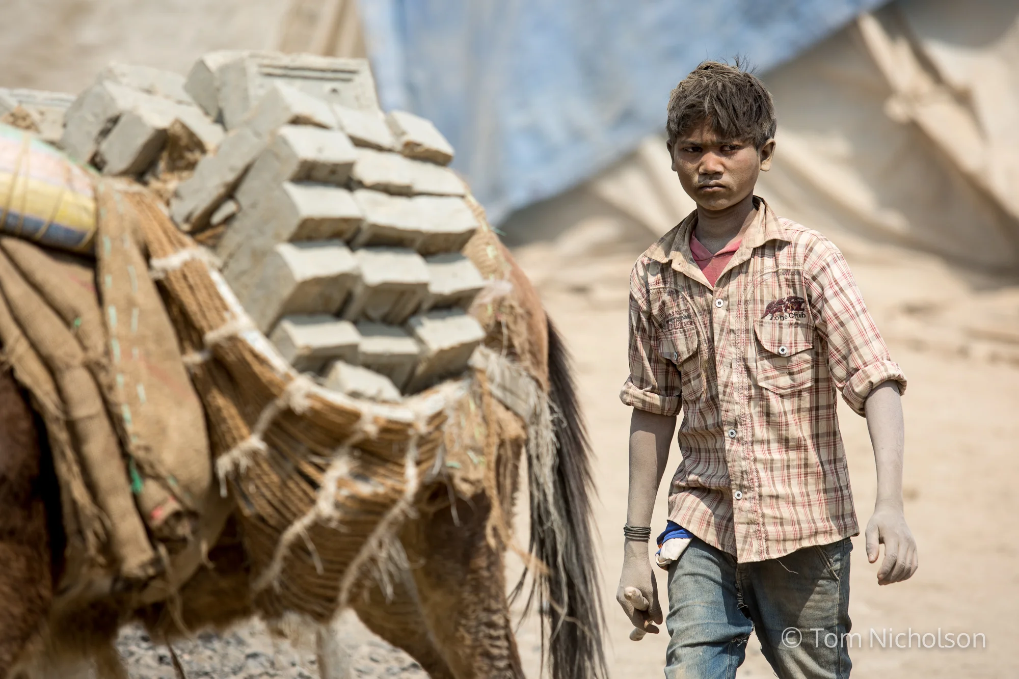 A child moves bricks in the UK brickworks factory in Bungamati, Kathmandu, Nepal on 15 March 2016. Around 400 labourers, including children, work in very dusty and hot conditions.