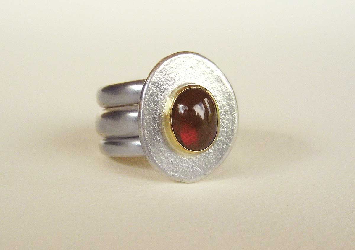 Silver ring with a garnet set in 18ct. gold