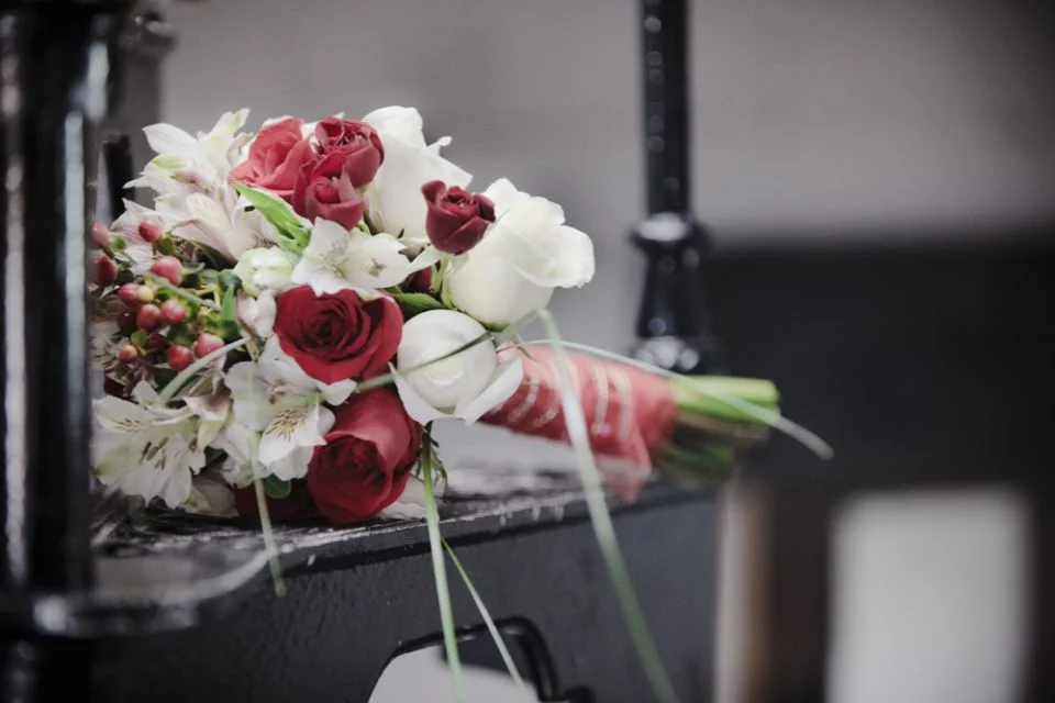 A bouquet of red roses, white flowers, and green foliage lying on a dark surface.