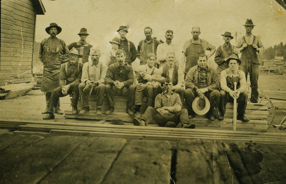 Entrance to Pearce Lumber Mill Tim Blackcommented: My mother (Virginia Black) tells me that the man on the very left with the goofy hat and the apron is my great grandfather Allan McGarvey SR and cousin Turk McGarvey front row 4th from left with arm out and Jim Gordenier beside Turk