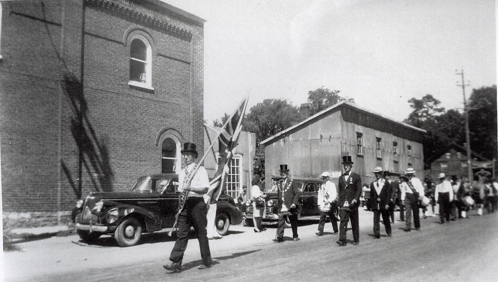 July 12th parade with Charles Dunlay in the lead,, on the now #7 highway, heading west. The Brick building is the O'Neill building which later become the TD Bank in Marmora. In the centre is tne blacksmith shop of Charles Sr. & Eli Clairmont. Far right the Clairmont house is visible. This house was later moved north, opposite the Town Hall (11 Bursthall St)