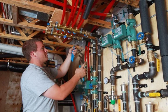 Brent McRoberts makes a final connection on a brass manifold to prepare for the startup of the new in-floor heating system.
