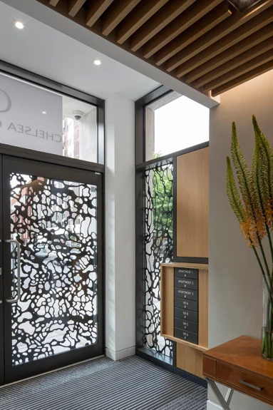  Double glazed entrance doors function as the public art requirement of the planing conditions. The artwork was etched into the void face of the glass and then bronzed to create a strong contrasting pattern that also provides some screening. 