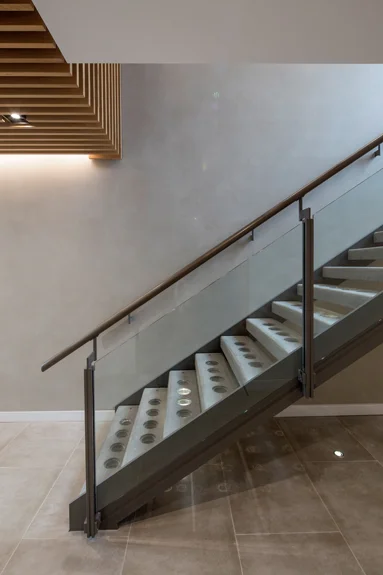  The pre-cast concrete stair treads have integral glass lenses combining both solid and transparent qualities, and allowing light to penetrate to the back of the entrance. A&nbsp;suede textured concrete&nbsp;wall finish and concrete effect tiles cont