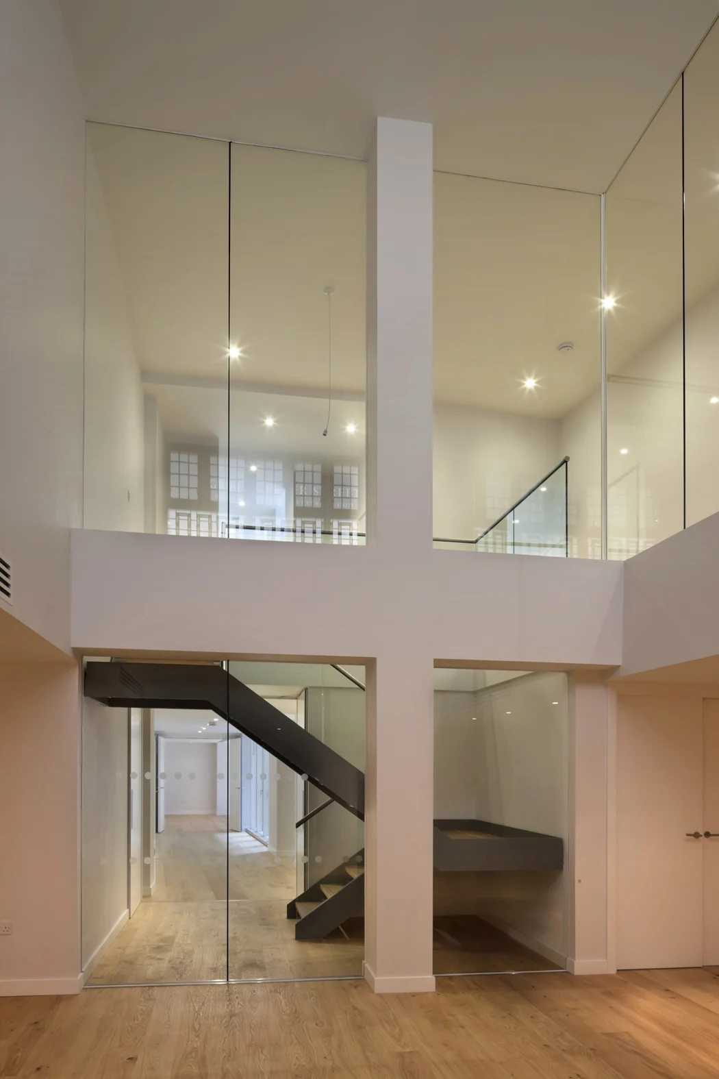  The main lounge and entertainment area is in an impressive double height space. The fire rated glazing allows this space to be connected to the ground floor entrance above and the rest of the lower ground living areas. 