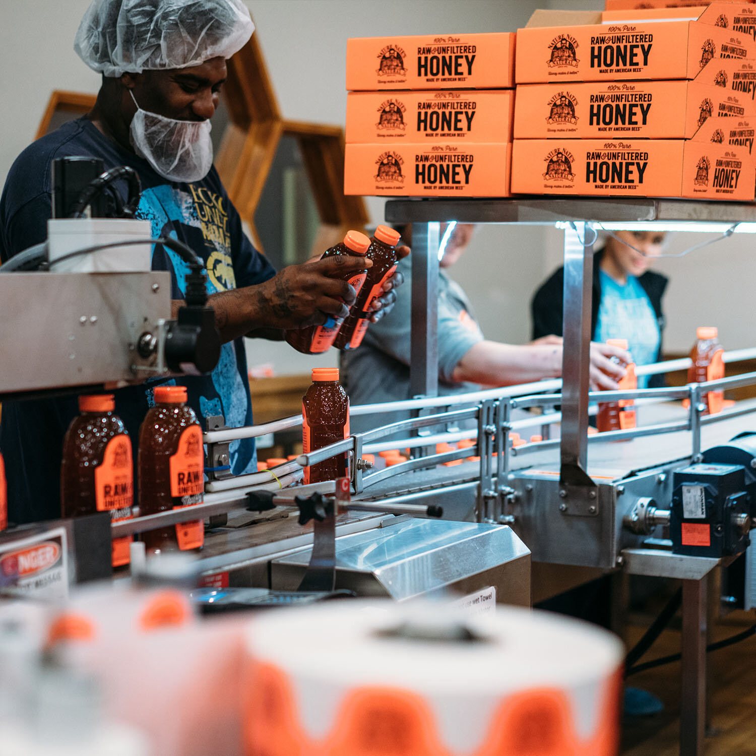 Production employees inspecting and packing Nature Nate's honey bottles on an assembly line in Texas