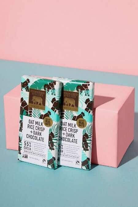 ESC's plant-based 3oz oat milk dark chocolate Gorilla bars propped up against a pink box for the Ellen DeGeneres BE KIND subscription box photo shoot