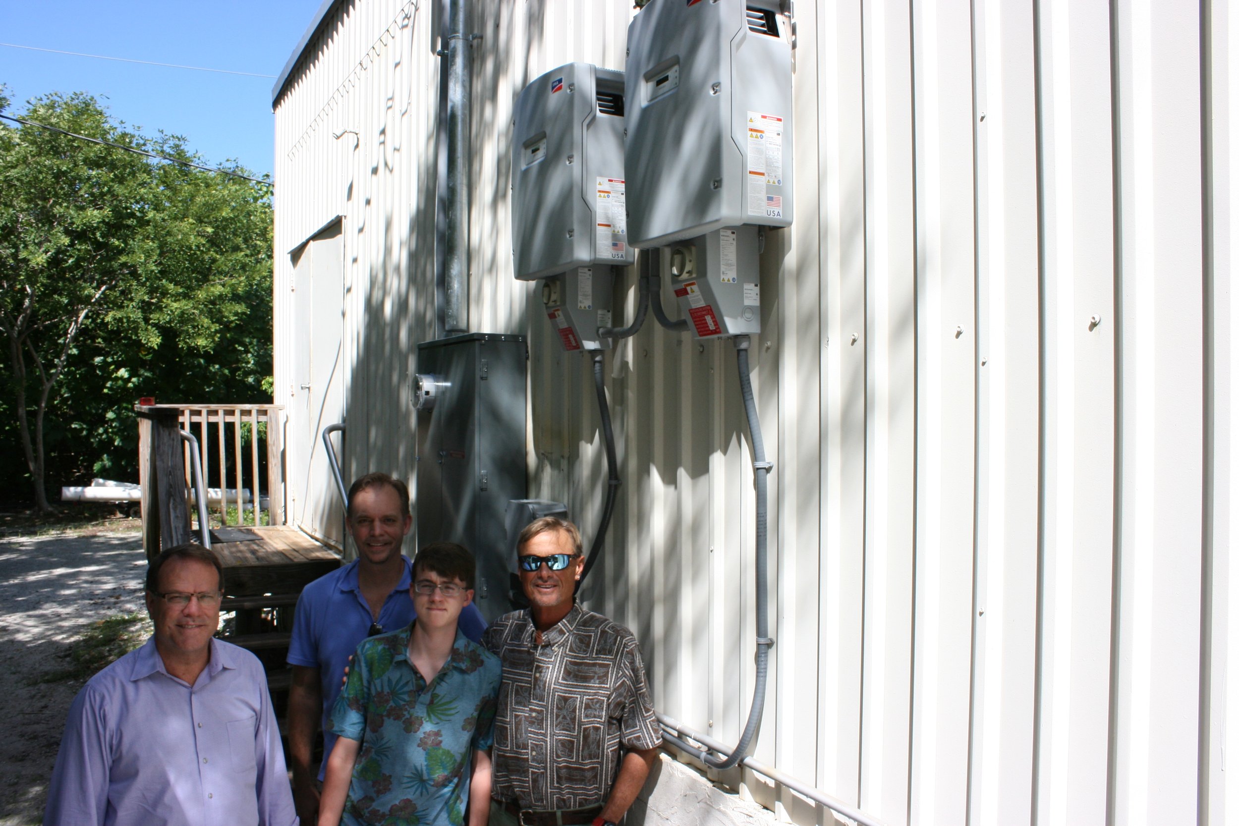 L to R: Dell Jones and Rudy Wodrich of Solar Utility Partners of Estero, Conrad Wodrich, a long-time Sanibel Sea School student, and Dr. Bruce Neill, Sanibel Sea School's Executive Director, pose for a photo with the solar array control panels on activation day. 