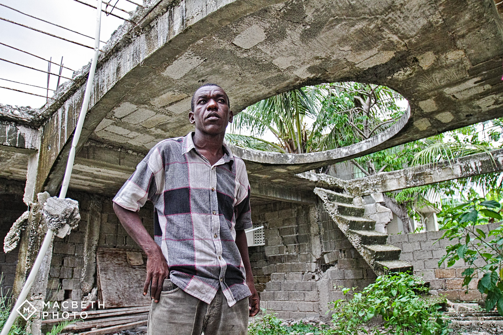 John Robert, earthquake survivor and REBUILD globally Supervisor and Designer. He is standing in what used to be his home prior to the earthquake. 