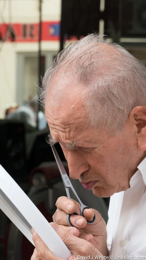 Just outside the Market, a local barber attends to his own grooming.