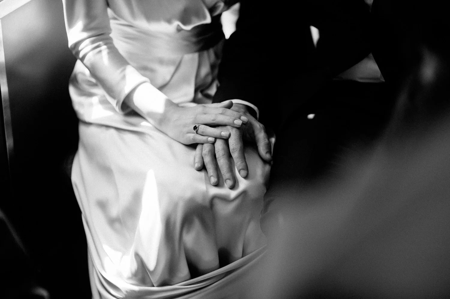 bride and groom tenderly touch hands in a wedding day detail photograph in black and white