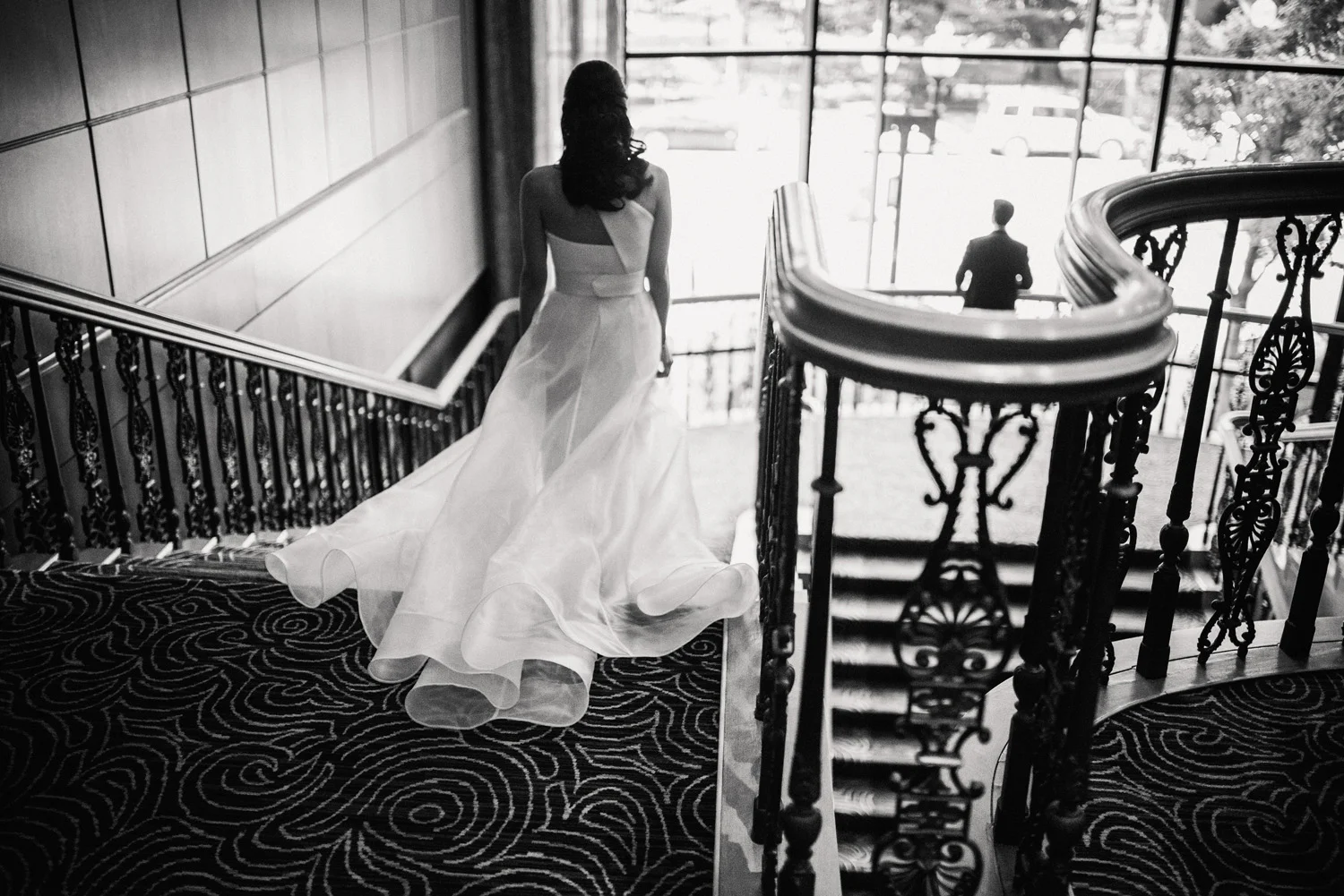 Bride walks down the grand staircase at the Boston Four Seasons for her first look before her modern, urban wedding ceremony