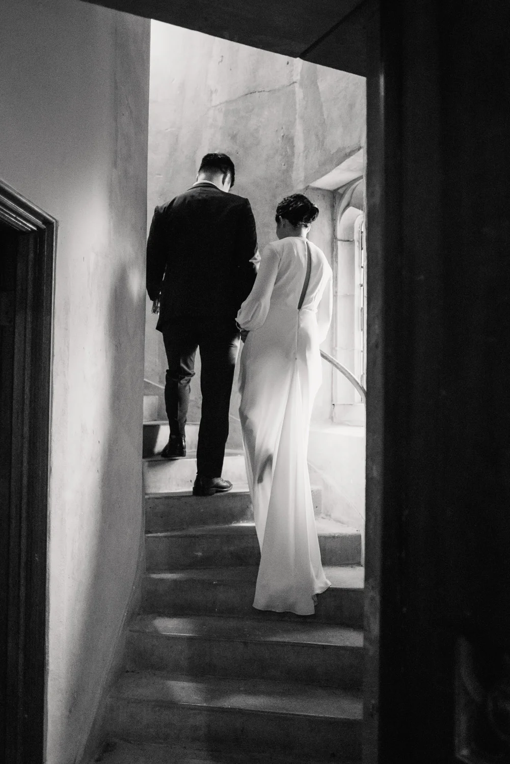 bride and groom walk up the stair of a church black and white wedding photography
