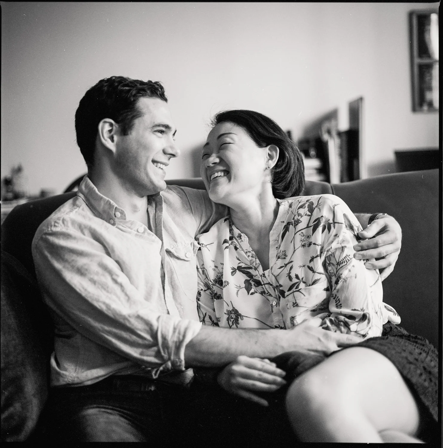 engagement photo couple sits on couch at home black and white film