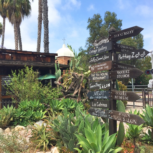 Wooden signs in San Juan Capistrano's Los Rios District with the train depot in the background.