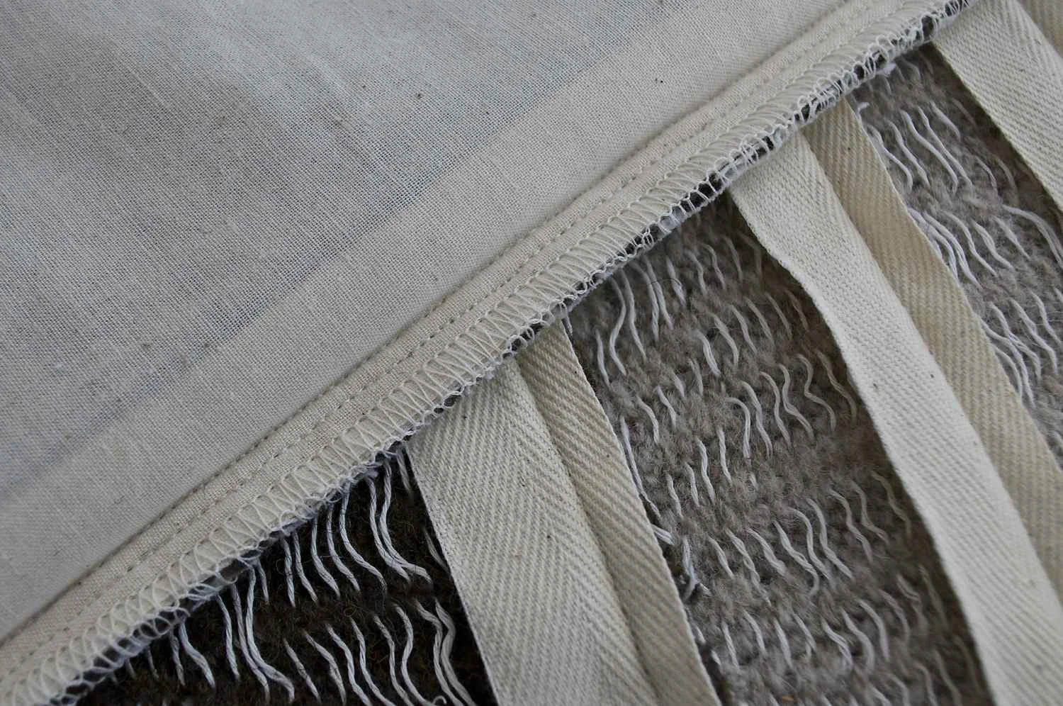The top fabric panel has a finished, serged edge. The fabrics underneath have been sewn with the twill tape only and are awaiting the muslin lining and other finishing touches.