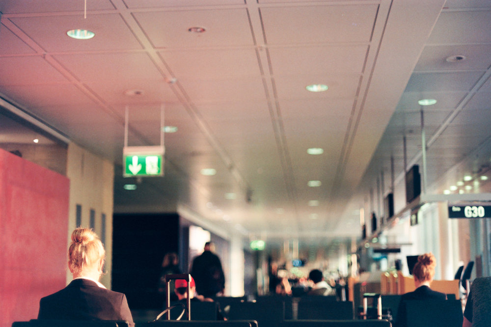 Flughafen München (Airport Munich). Everyday in the passenger terminal. Side lighting from the right - sun. And shallow depth of field to draw attention to the subject matter (s). Air hostesses waiting for their departing workplace. Mystery lines of the ceiling lights leading into the endless abyss of the terminal.