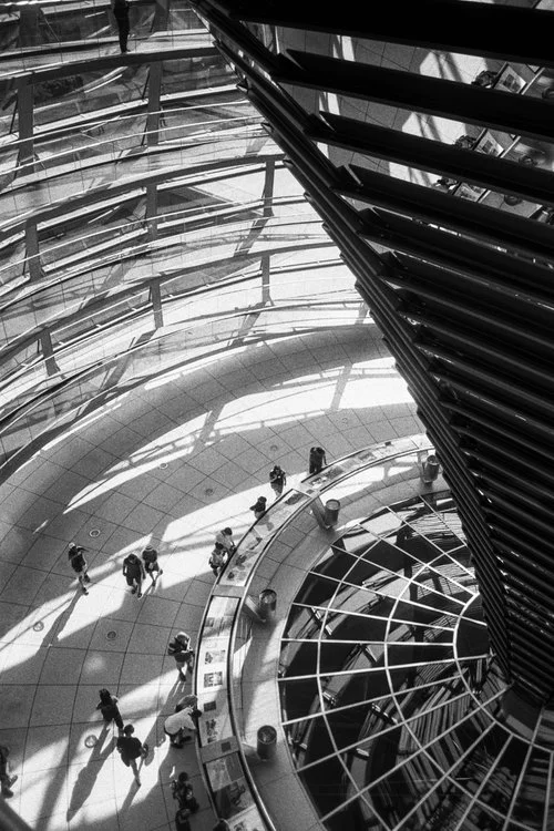 Bundestag, Berlin . After WW2 and after many revisions with a well-renowned Architectural Firm, the new structure incorporating vast glass louvres, allowing transparency of the ruling government with people of Germany. Natural light reflecting off of the inner corner structure with angled mirrored glass creating a wonderful effect.