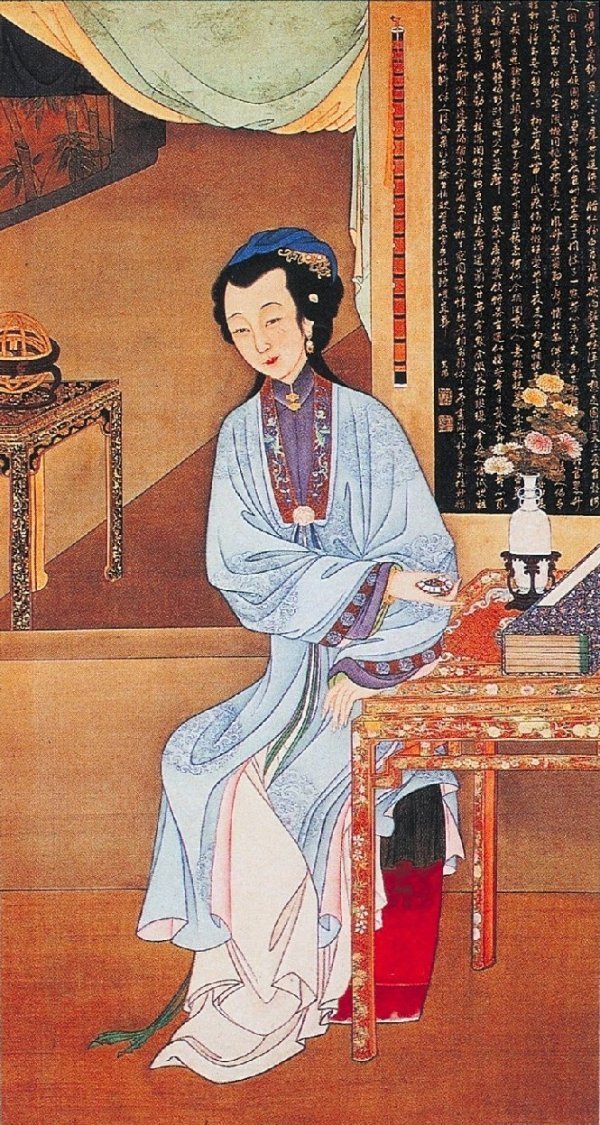 2,持表對菊:仕女手持精美的琺琅表坐於書案旁。桌上瓶中插有菊花,點明了時值八月時節。菊花清高典雅,是秋季重要的觀賞花卉,被賦予堅貞、益壽等含義,同時又以其素凈優雅的自然美而成為女性的頭飾或居室的點綴品。背景牆面上懸挂著明代董其昌的詩句。
