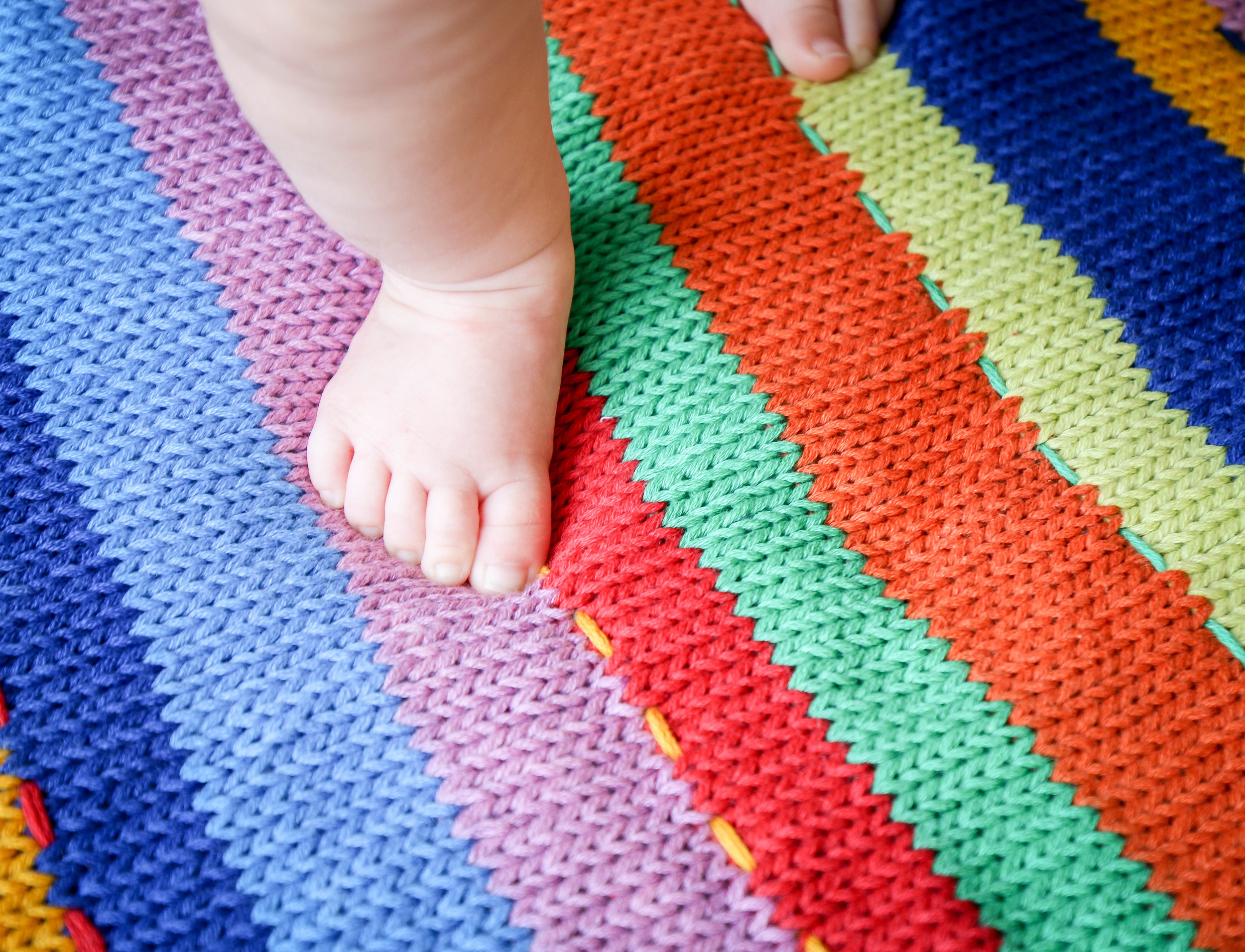 Madeline practicing standing on a blanket made by her great-grandmother.
